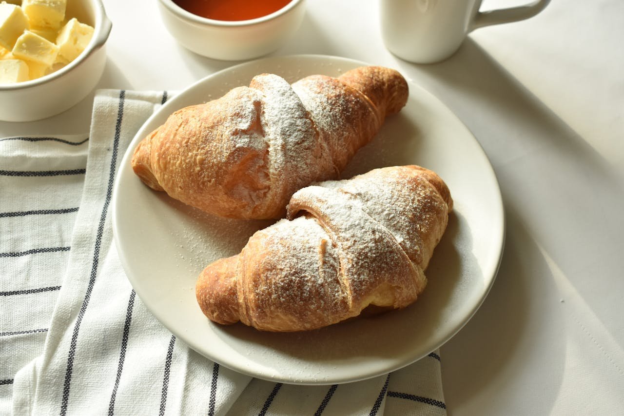 Tasty croissants served with butter and coffee on a bright morning.